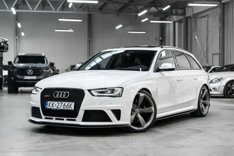 Białe Audi RS4 Avant z przyciemnianymi szybami i sportowymi felgami stoi w garażu.